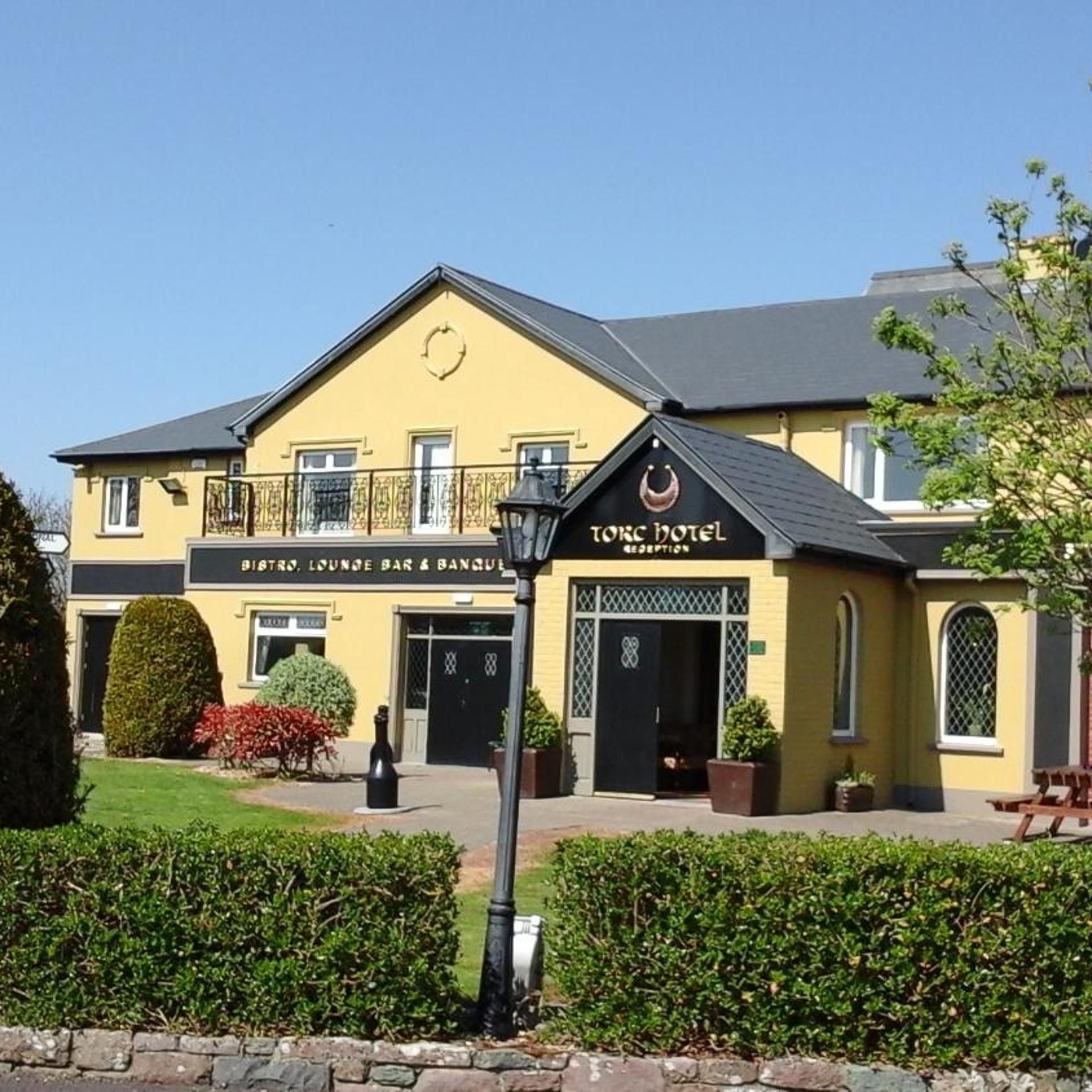 A yellow building with a sign for 'TORC HOTEL' and a separate sign for 'BISTRO, LOUNGE BAR & BANQUET'.