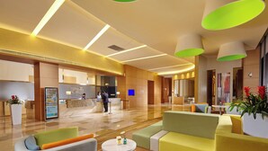 A modern hotel lobby with a reception desk, seating area, and a digital information kiosk. - Holiday Inn Express Shanghai Jiading Industry Park by IHG (Shanghai)