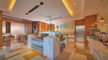 A modern hotel lobby with a marble reception desk, buffet area, and seating arrangements.