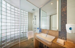 A modern bathroom with a glass shower enclosure, a sink with a mirror, and a towel rack.