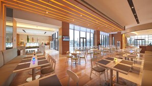 A spacious indoor dining area with multiple tables and chairs, a reception desk, and large windows allowing natural light. - Holiday Inn Express Shanghai Jiading Industry Park by IHG (Shanghai)