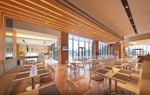 A spacious indoor dining area with multiple tables and chairs, a reception desk, and large windows allowing natural light. - Holiday Inn Express Shanghai Jiading Industry Park by IHG (Shanghai)