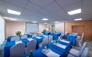 A conference room with multiple tables, chairs, and a projector screen.