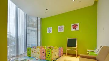 Children can play and create in this spacious room with a play area featuring foam blocks, a chalkboard, and a sofa for adults to relax.