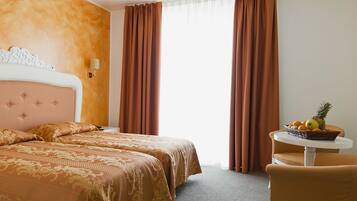 Una habitación de hotel con una cama doble, una mesita con fruta y un televisor en la pared.