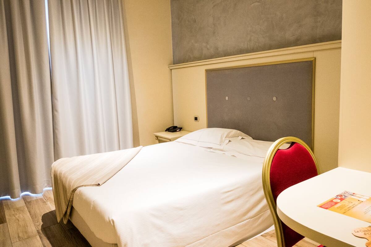 Een hotelkamer met een bed, nachtkastje, stoel en tafel.