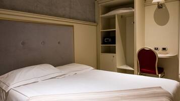 A hotel room with a bed, a wardrobe, and a vanity with a mirror.