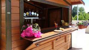 Un coin bar en bois avec un robinet à bière, un verre orné d’une fleur et un plateau rempli de collations.