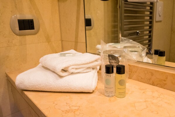 A bathroom counter with stacked white towels, a bottle of body wash, and a bottle of shampoo.