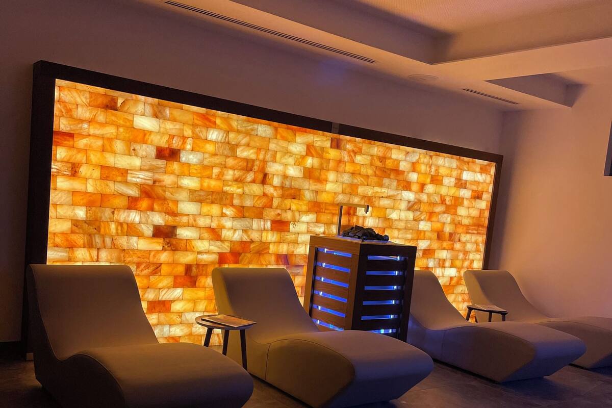 Een moderne ontspanningsruimte met drie lounge fauteuils, een klein tafeltje en een wand met een structuurpatroon.