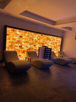 Un'area relax moderna con tre poltrone, un tavolino e un muro con motivo decorativo.