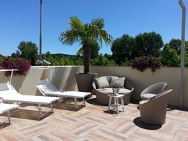 Una terrazza sul tetto con poltrone da relax, un tavolino e una palma in vaso.