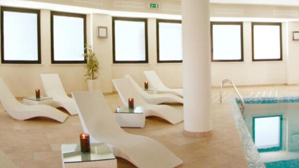 A spa area with lounge chairs, a pool, and a potted plant. - Hotel Novarello  (Granozzo con Monticello)