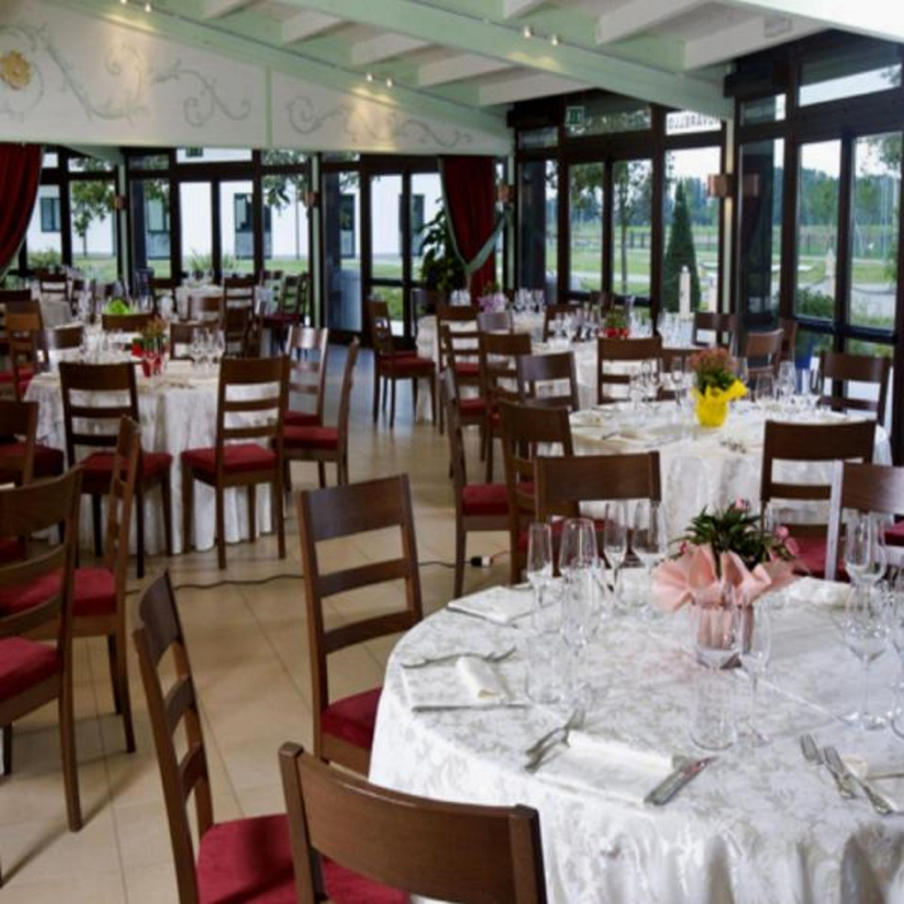 A dining area with round tables set for a meal, surrounded by chairs.