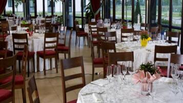 A dining area with round tables set for a meal, surrounded by chairs.