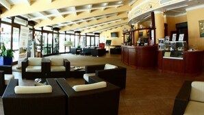 A spacious lobby with high ceilings, a curved reception desk, and comfortable seating areas. - Hotel Novarello  (Granozzo con Monticello)