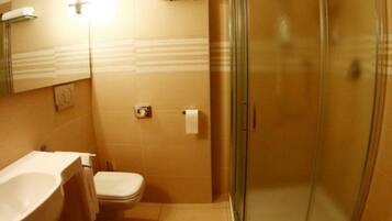 A bathroom with a glass-enclosed shower, a toilet, and a sink.