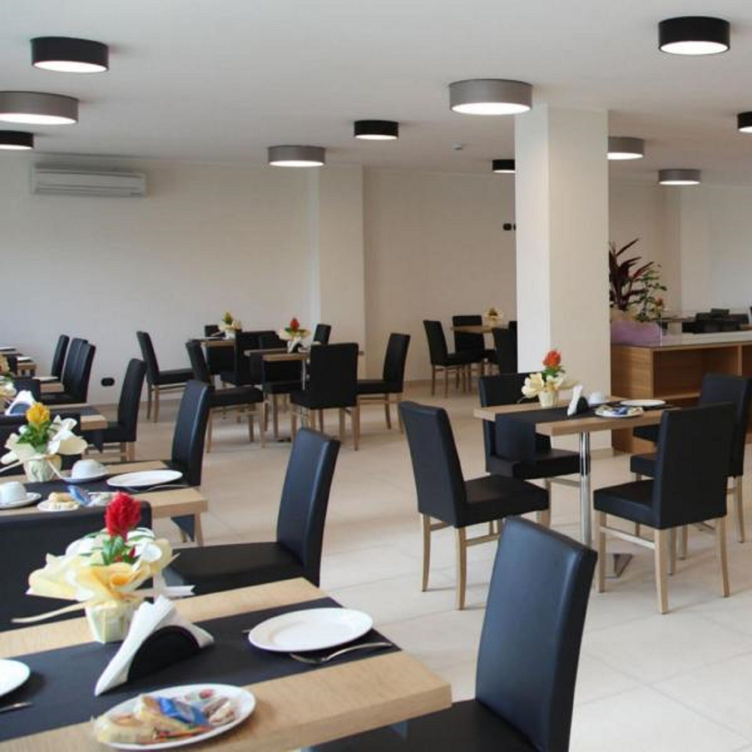 A dining area with tables set for meals, chairs, and a counter with a plant.