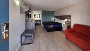 A hotel room with a bed, a red sofa, a desk with a phone, a mirror, and a window. - Budget Inn Roxboro (Roxboro)