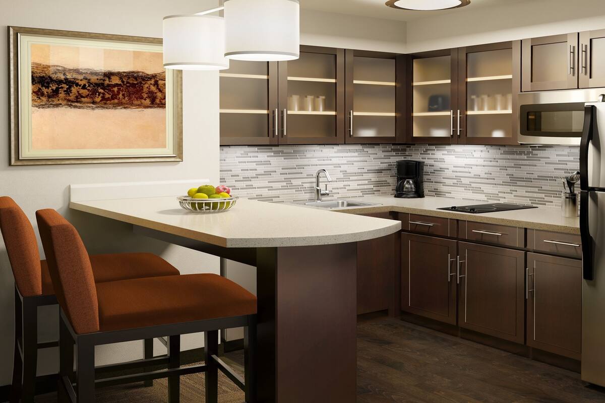 A modern kitchen with a central island, stainless steel appliances, and a tiled backsplash.