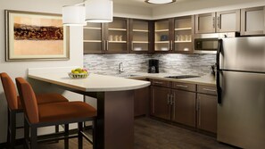 A modern kitchen with a central island, stainless steel appliances, and a tiled backsplash. - Staybridge Suites Dearborn MI by IHG (Dearborn)