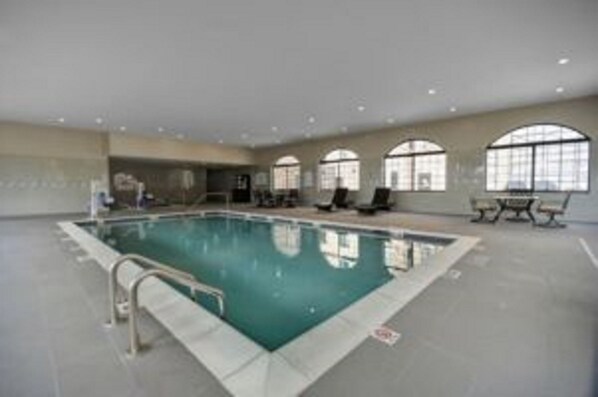 An indoor swimming pool with clear glass walls, a tiled floor, and a few lounge chairs. - Staybridge Suites Dearborn MI by IHG (Dearborn)