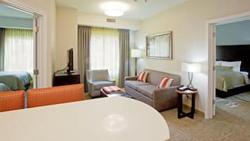 A hotel room with a bed, a sofa, a chair, a table, and a lamp.
