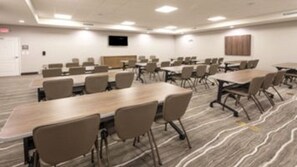 A conference room with multiple tables and chairs, a flat-screen TV mounted on the wall, and a patterned carpet. - Staybridge Suites Dearborn MI by IHG (Dearborn)