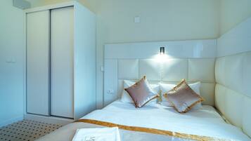 A hotel room with a bed, a wardrobe, and a bedside table.