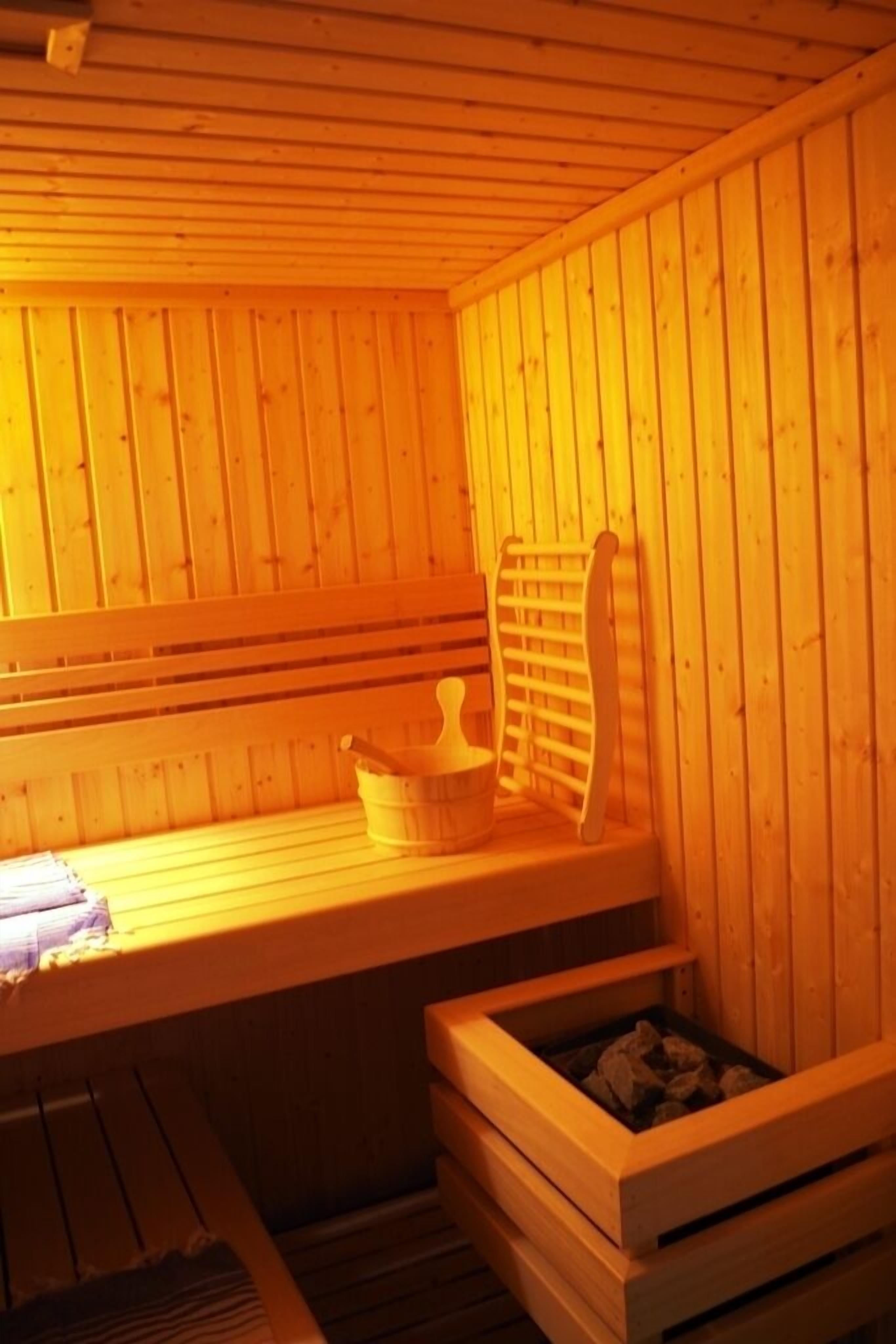 Un sauna en bois avec des bancs, un banc muni d’une serviette et un porte-serviettes en bois.