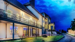 A large, two-story house with a balcony, a covered porch, and a well-maintained lawn. - Boutique Apartmenty M&M (Mikolajki)