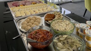 A buffet table with various food items and a glass display case. - Boutique Apartmenty M&M (Mikolajki)