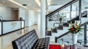 A modern hotel lobby with a reception desk, a staircase, and a seating area. - Boutique Apartmenty M&M (Mikolajki)