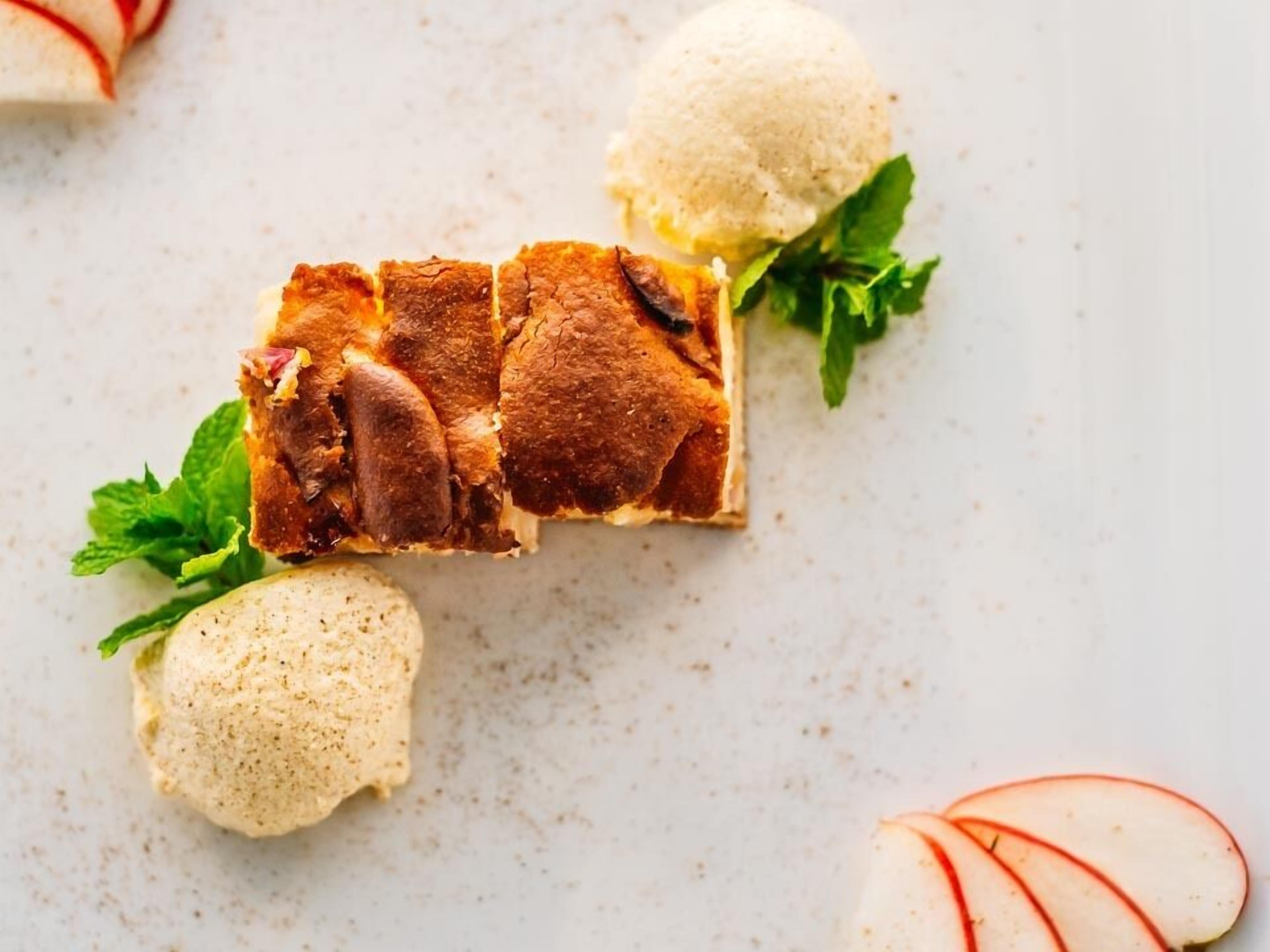 A dessert plate with a slice of cake, a scoop of ice cream, and apple slices.