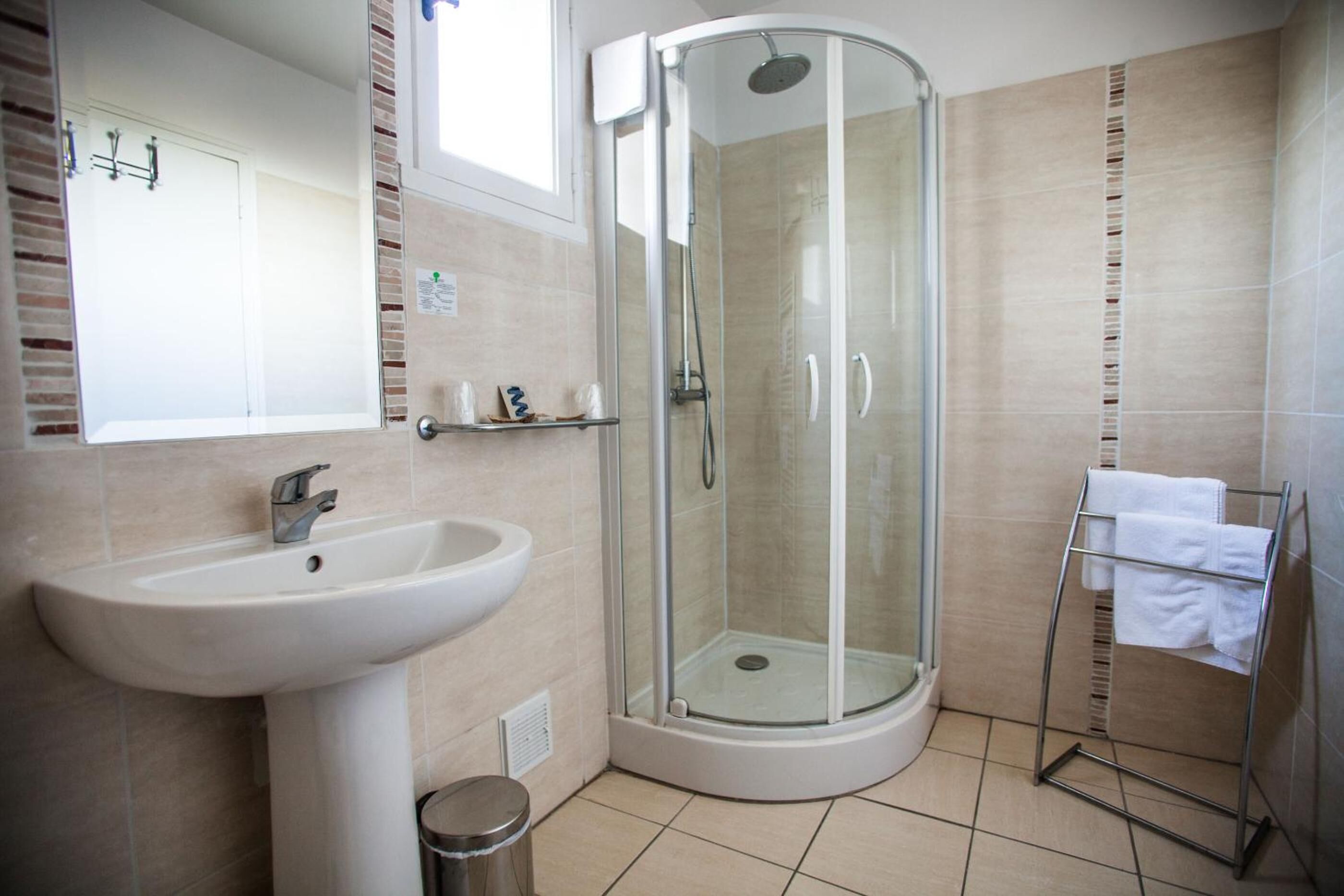 A bathroom with a glass-enclosed shower, a sink, and a towel rack.
