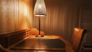 Een houten tafel met een lamp, een stoel en een muur met een structuur.