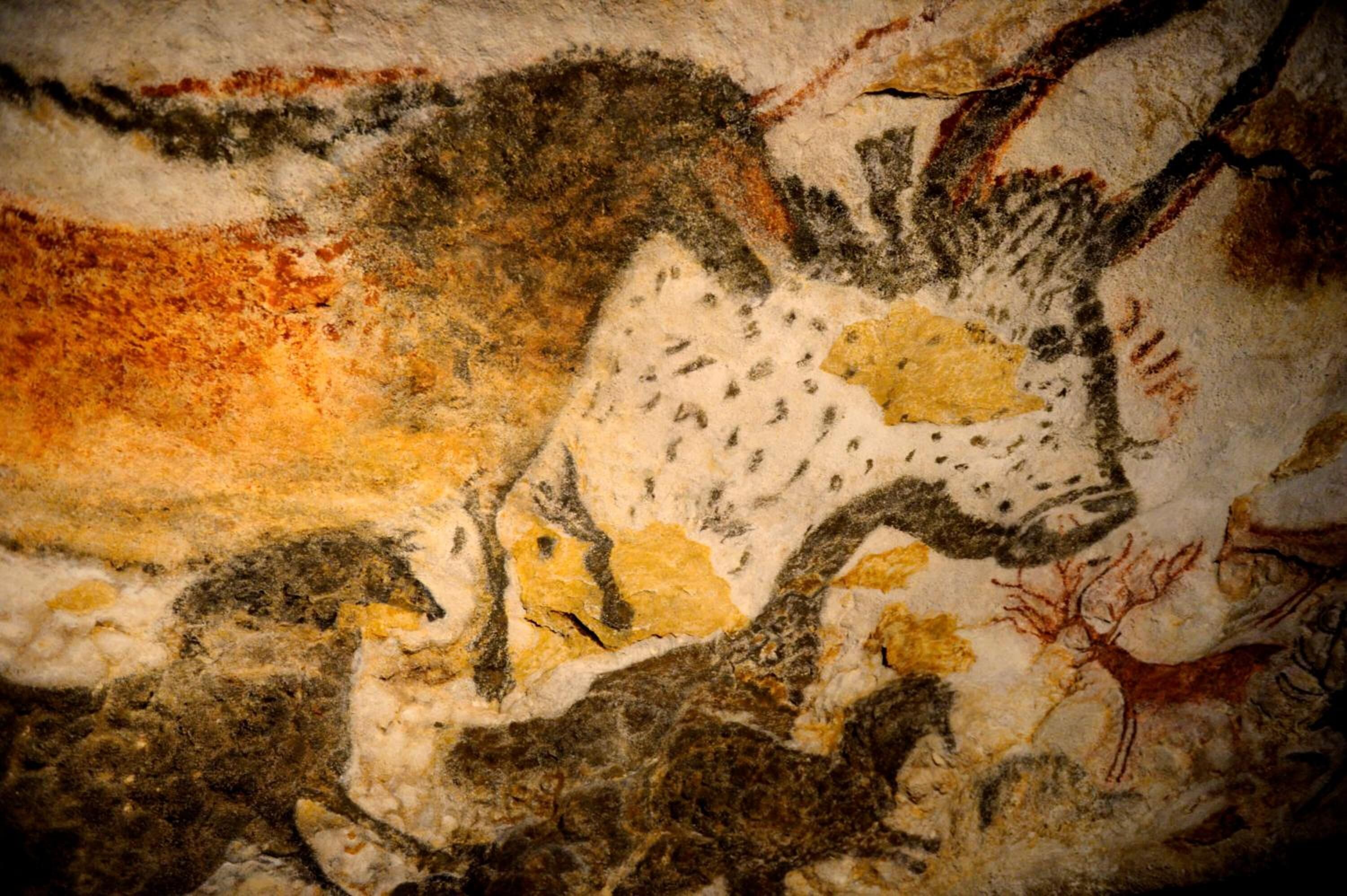 A cave wall with prehistoric cave paintings, including animals and human figures.