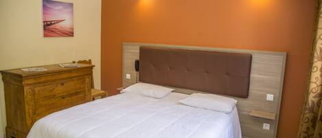 A bedroom with a large bed, a wooden dresser, and a painting on the wall.