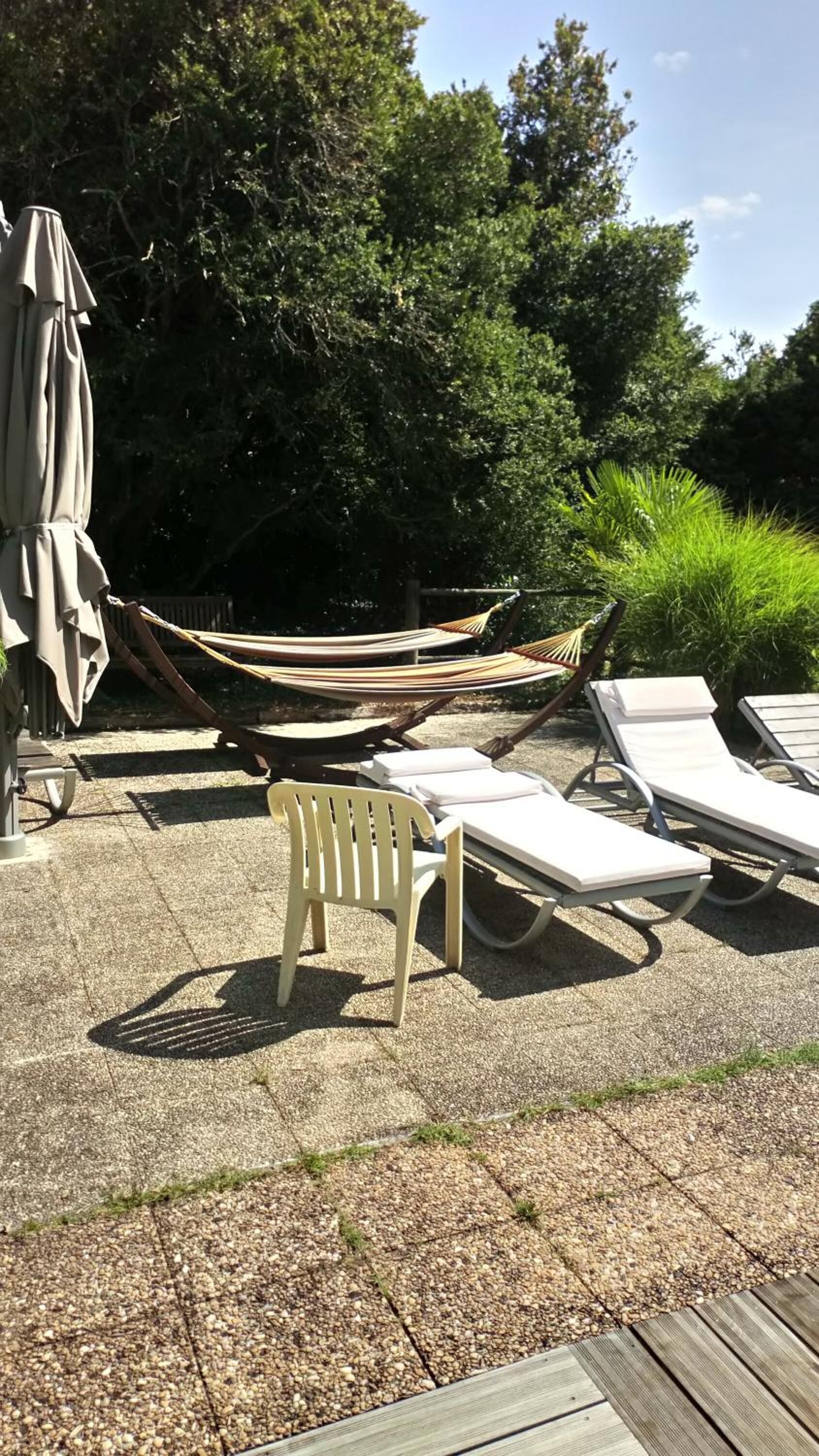 Een terras met lounge stoelen, een hangmat en een houten dek.