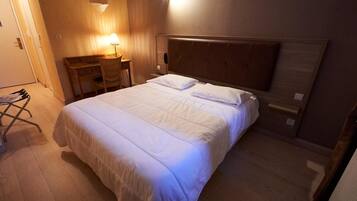 Un letto rifatto con lenzuola bianche in una camera d'albergo.