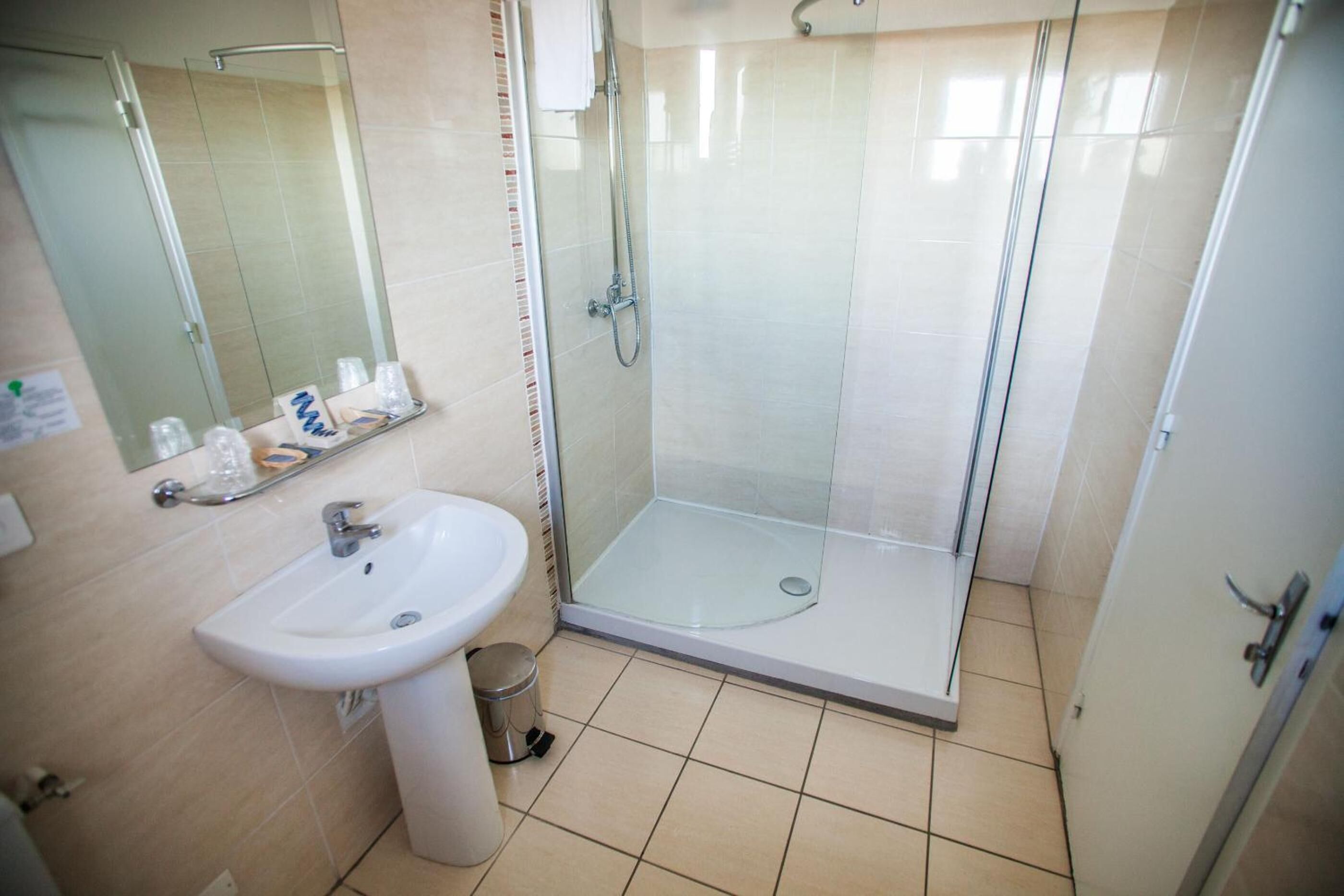 A bathroom with a glass-enclosed shower, a sink, and a mirror.