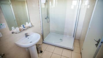 A bathroom with a glass-enclosed shower, a sink, and a mirror.