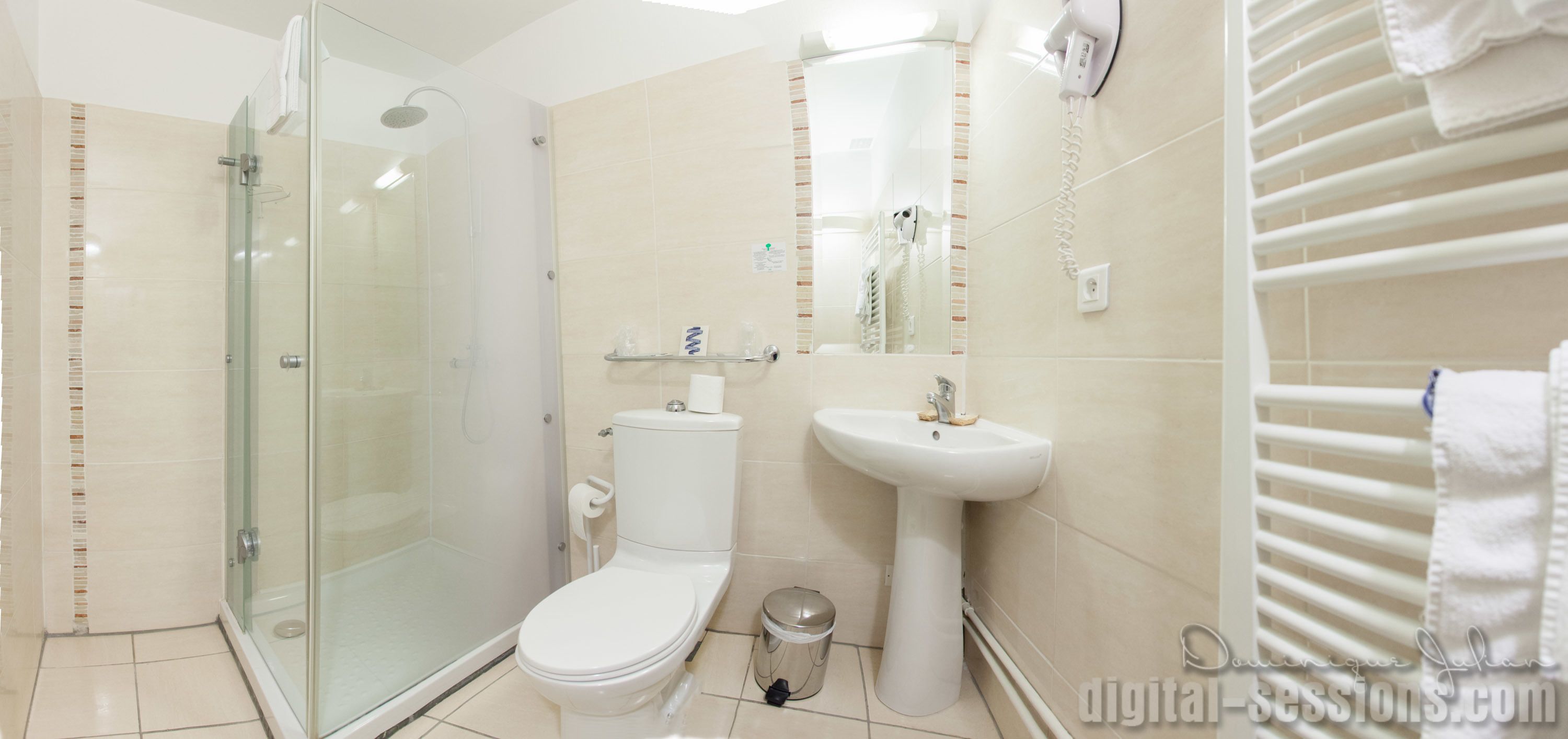 A modern bathroom with a glass-enclosed shower, a white toilet, a pedestal sink, and a towel rack.
