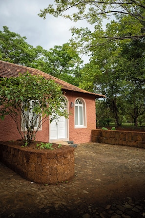 A rustic building with a tiled roof, a white door, and a stone wall. - Belo Monte - Principe Collection (Príncipe Island)