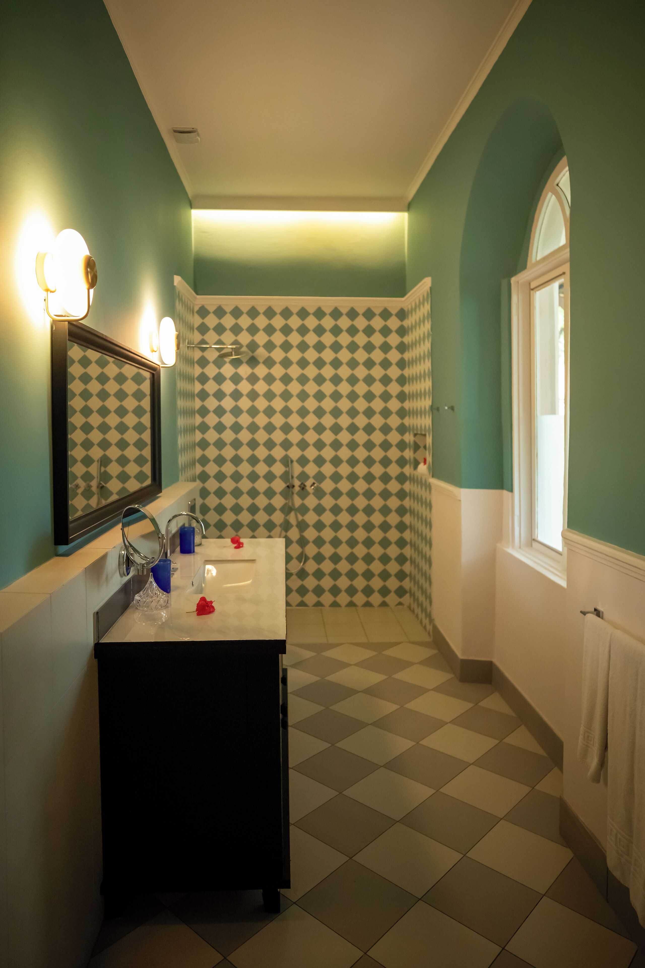 A bathroom with a checkered floor, a sink with a mirror, and a window.