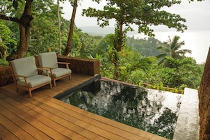 Terraza de madera con dos sillas y una piscina pequeña.