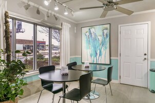 Une salle de conférence avec une table ronde, des chaises noires, un ventilateur de plafond et un grand tableau abstrait accroché au mur.