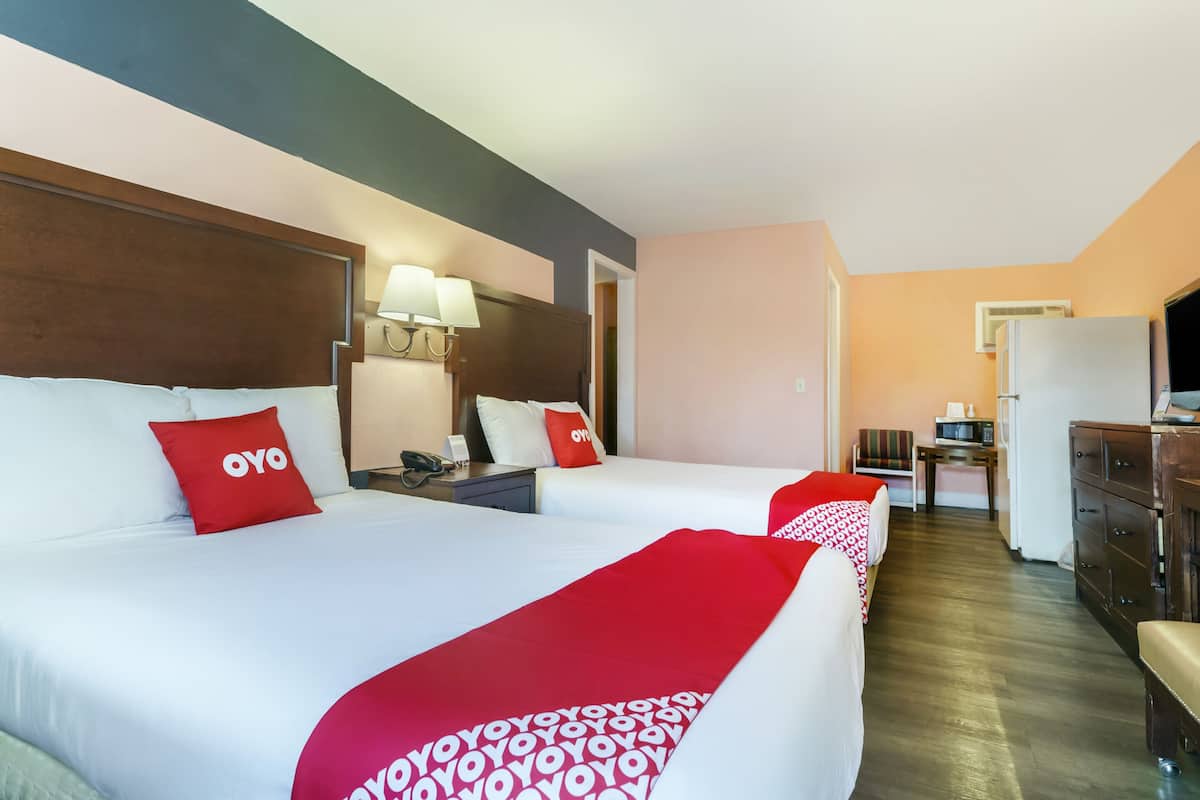 Habitación de hotel con dos camas, un escritorio, un refrigerador y un microondas.