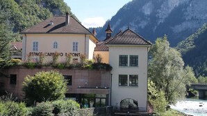 A building with a sign reading "ESPACE CARPETA & SONS" and a river in the background. - Cit’Hôtel Le National (Cluses)