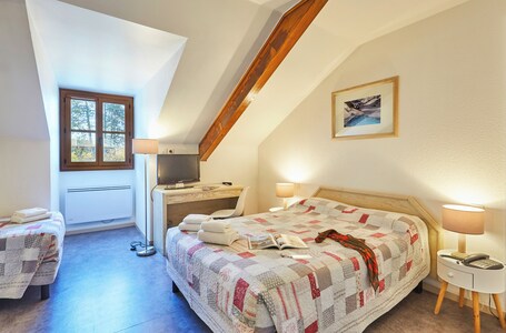 A bedroom with a large bed, a desk, a chair, a window, and a painting on the wall.
